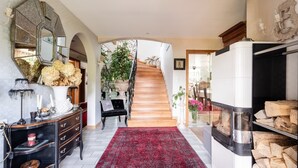 Un hall d’entrée spacieux avec un escalier en bois, une cheminée et un grand miroir.