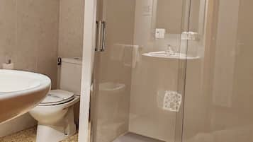 A bathroom with a glass-enclosed shower, a toilet, and a sink.