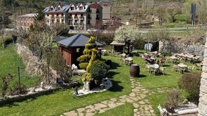 Un hotel con patio, mobiliario exterior y vistas a las colinas circundantes.