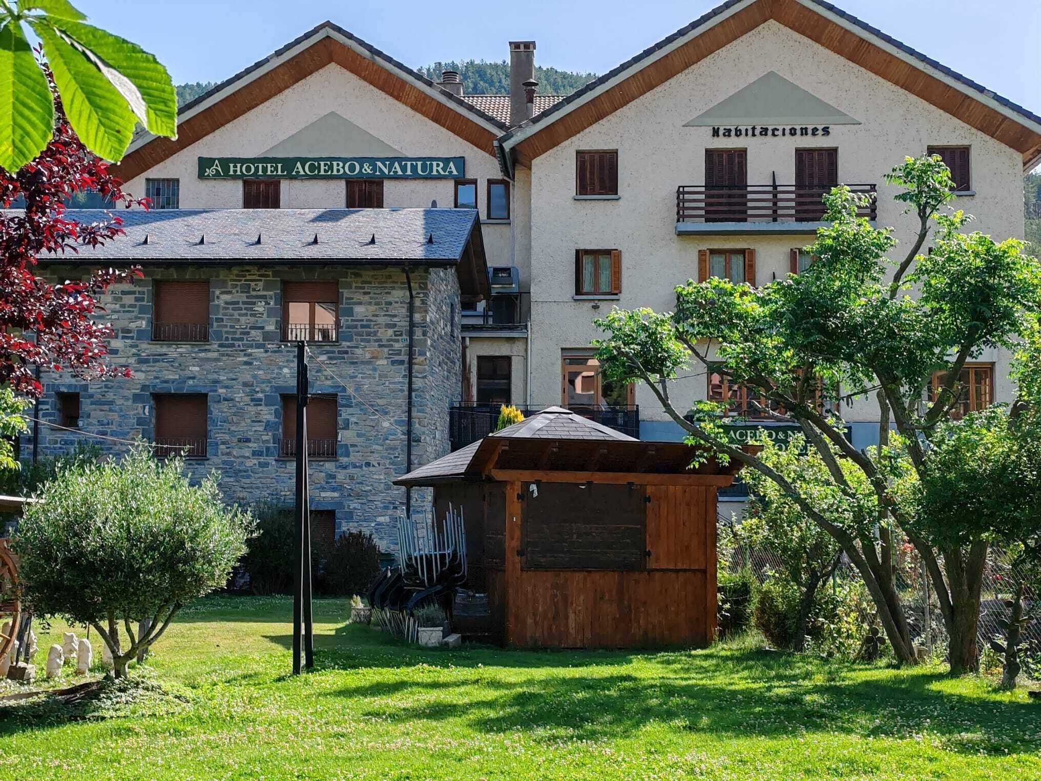 Un hotel con facciata in pietra, balconi in legno e un cartello che riporta la scritta 'HOTEL ACEBO&NATURA'.