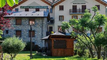 Un hotel con facciata in pietra, balconi in legno e un cartello che riporta la scritta 'HOTEL ACEBO&NATURA'.