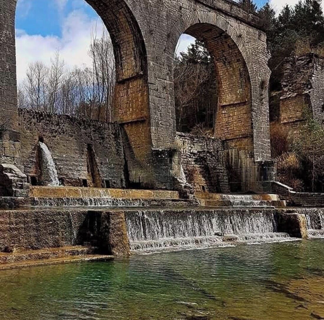 A stone bridge with arches over a body of water.