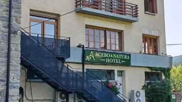 Ett hotell med en skylt där det står ”ACEBO & NATURA HOTEL”, en trappa och luftkonditioneringsaggregat.