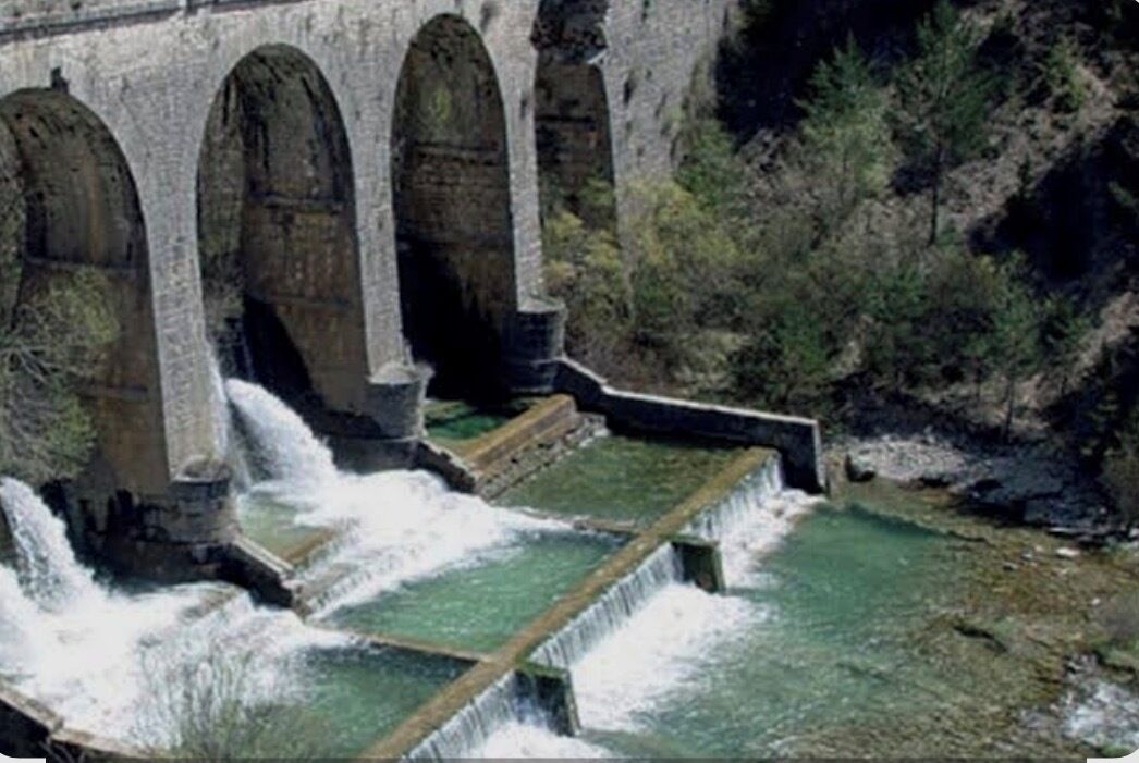 A stone dam with multiple arches and water cascading down.