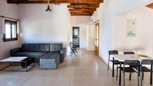 A modern interior with a sectional sofa, dining table, chairs, and a ceiling with exposed beams.