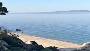 A coastal beach with rocky terrain and a clear view of the sea.