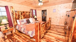 Interior de una cabaña de madera con una cama, un ventilador de techo, una mesita de noche y un armario.