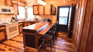 Una cocina estilo cabaña de madera con una isla central, armarios de madera, un microondas y una estufa.