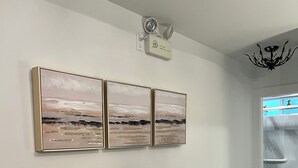 Ein Flur mit Wandleuchte zur Notbeleuchtung, einem braunen Ledersessel und einer Glastür zu einem Badezimmer.
