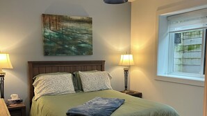 Ein Schlafzimmer mit einem Bett, zwei Nachttischlampen, einem Fenster und einem Bild an der Wand.