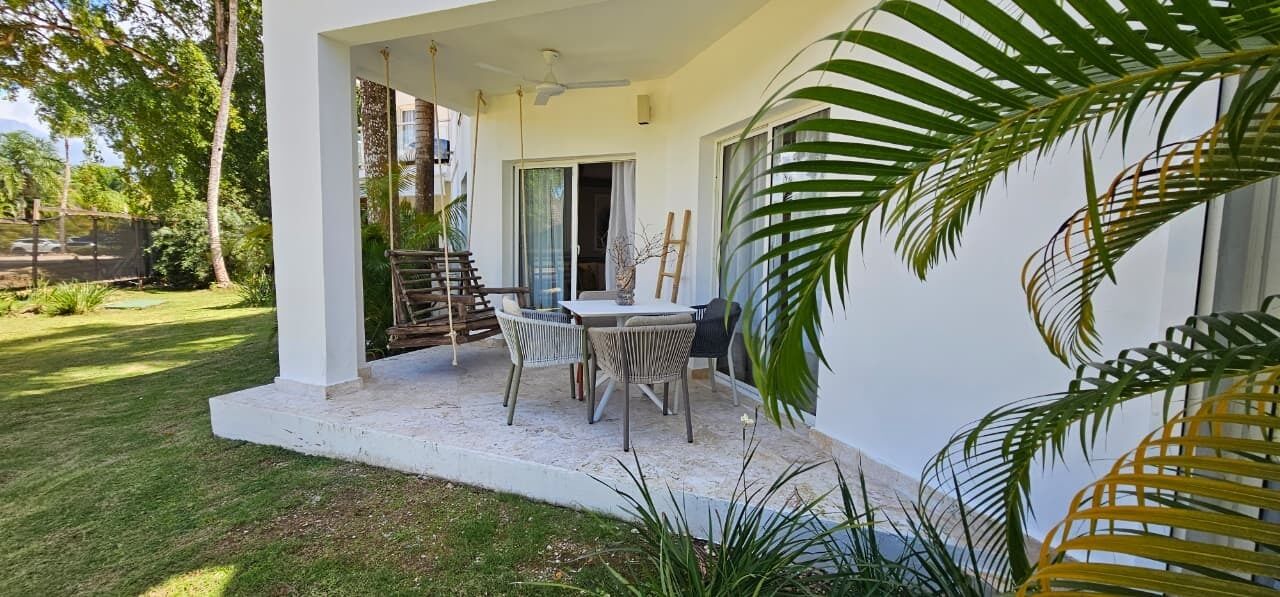 A patio with a table and chairs, a covered area, and a view of the surrounding greenery.