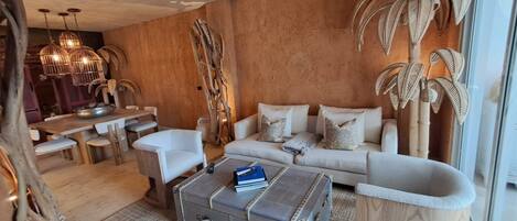 A modern living room with a sofa, coffee table, and a dining area with a table and chairs.
