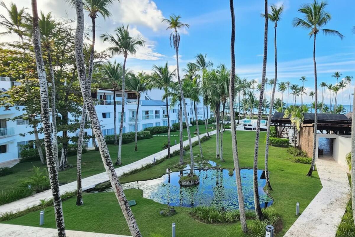 A resort with a pool, palm trees, and a clear sky.