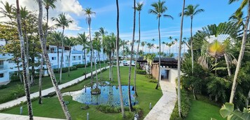 A resort with a pool, palm trees, and a clear sky.