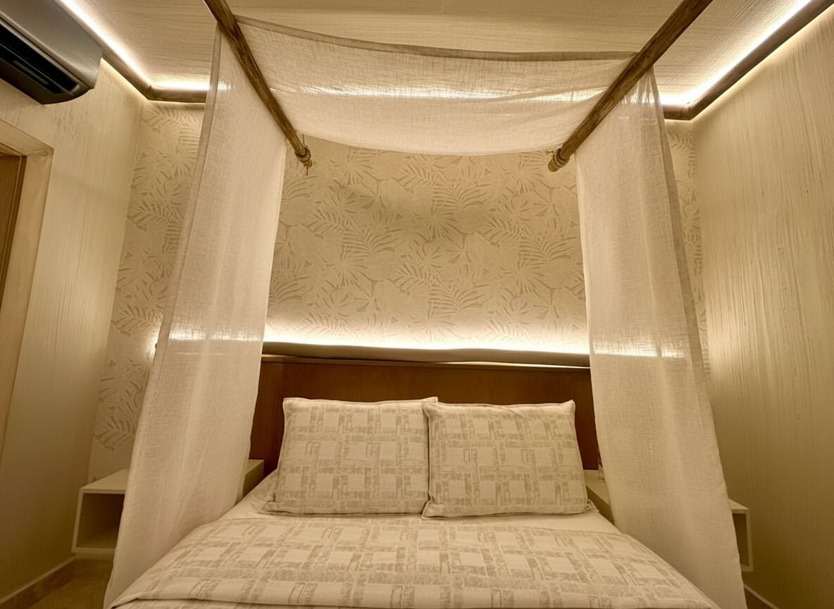 A bedroom with a canopy bed, a headboard, and a bedside table.