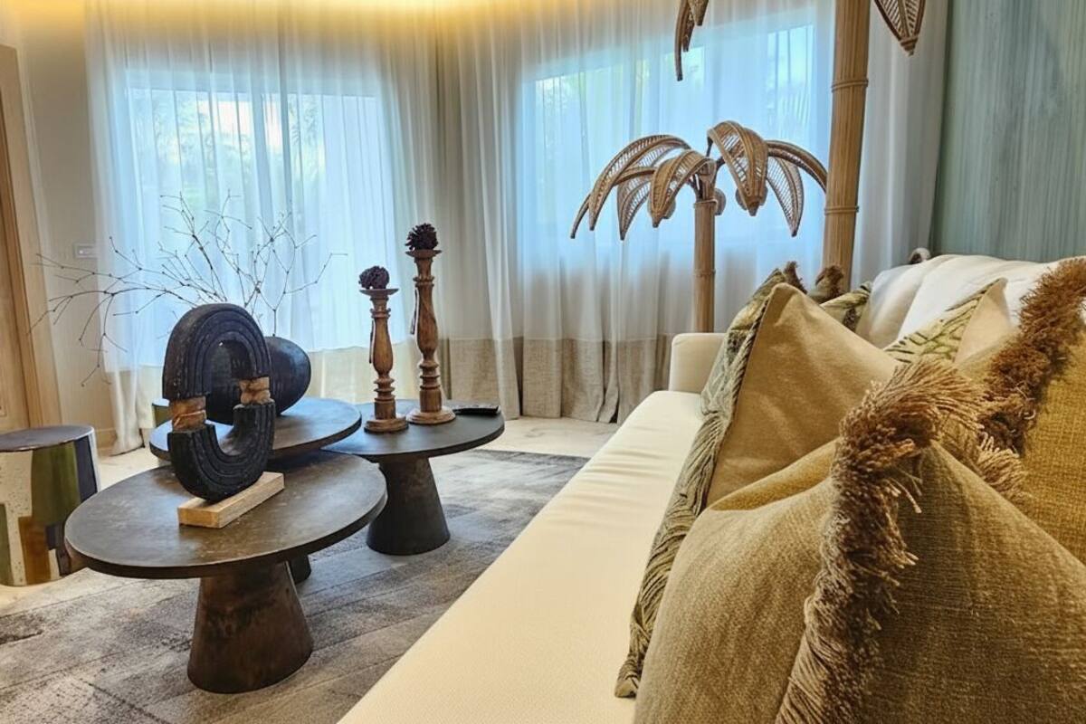 A living room with a sofa, two round tables with decorative items, a television, and a door.