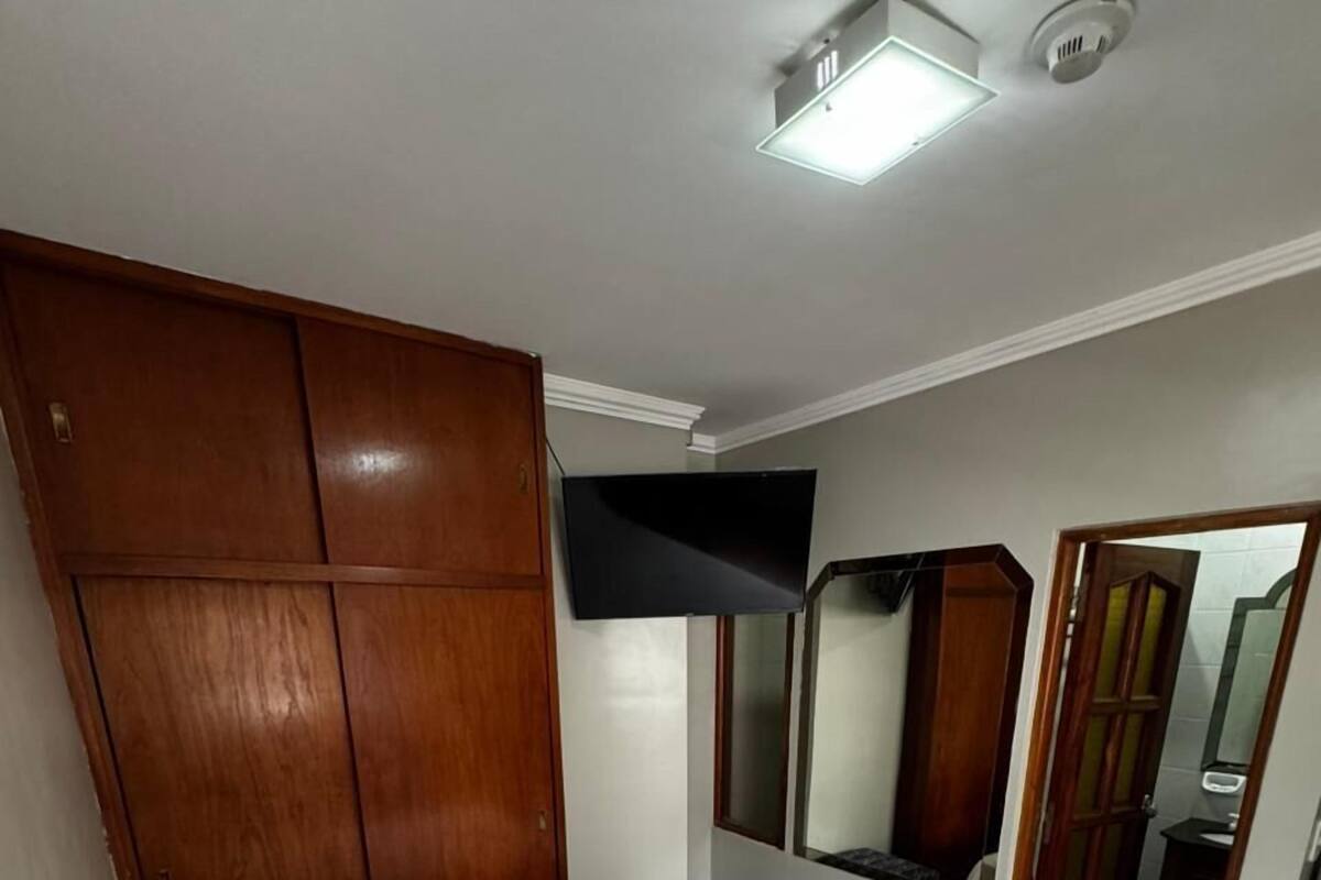 Une chambre à coucher avec un lit, une armoire, un miroir et un luminaire au plafond.