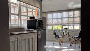 Una cocina moderna con microondas integrado, refrigerador y comedor con mesa y sillas.