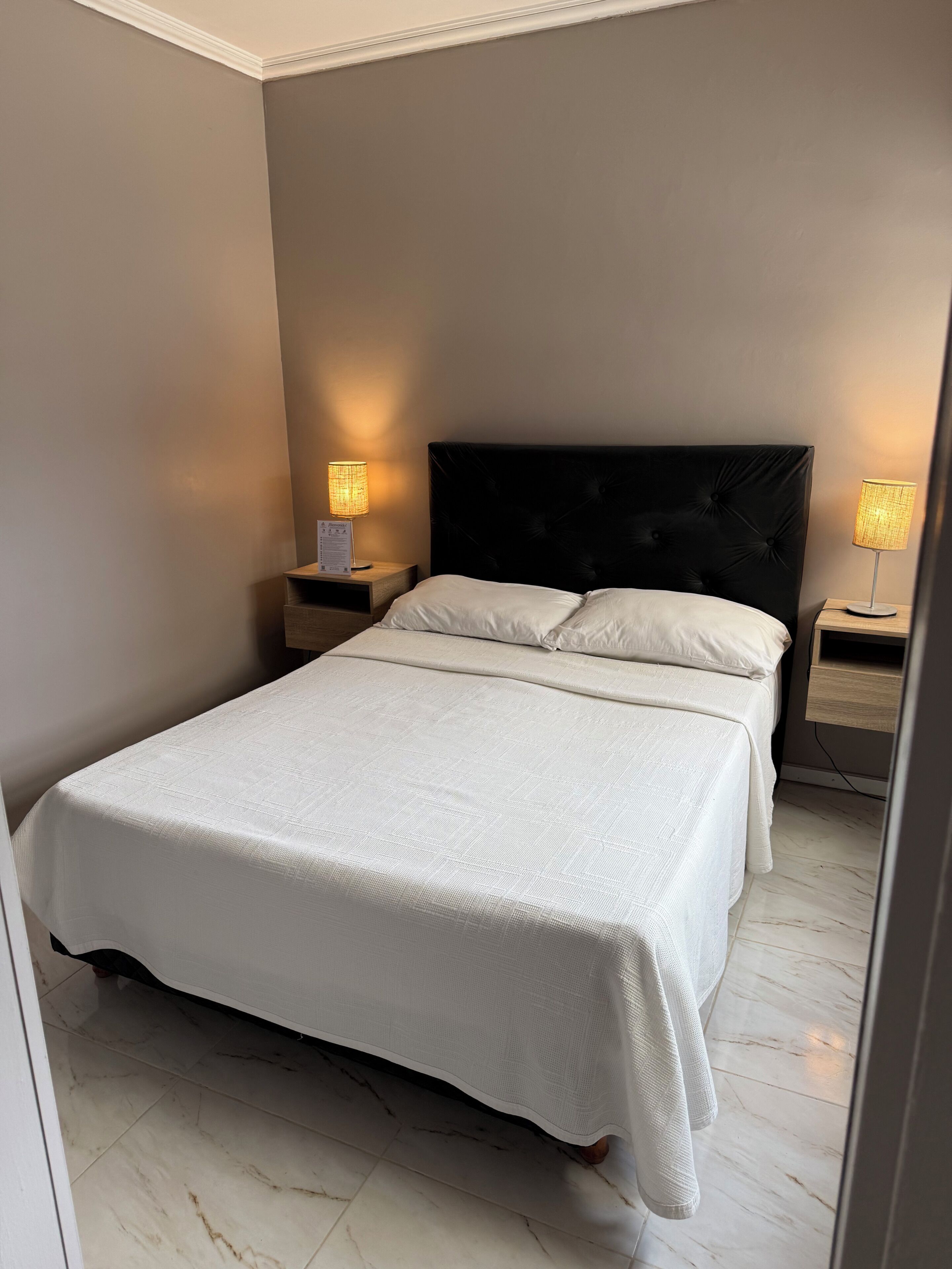 Un dormitorio con una cama, dos mesitas de noche y dos lámparas.