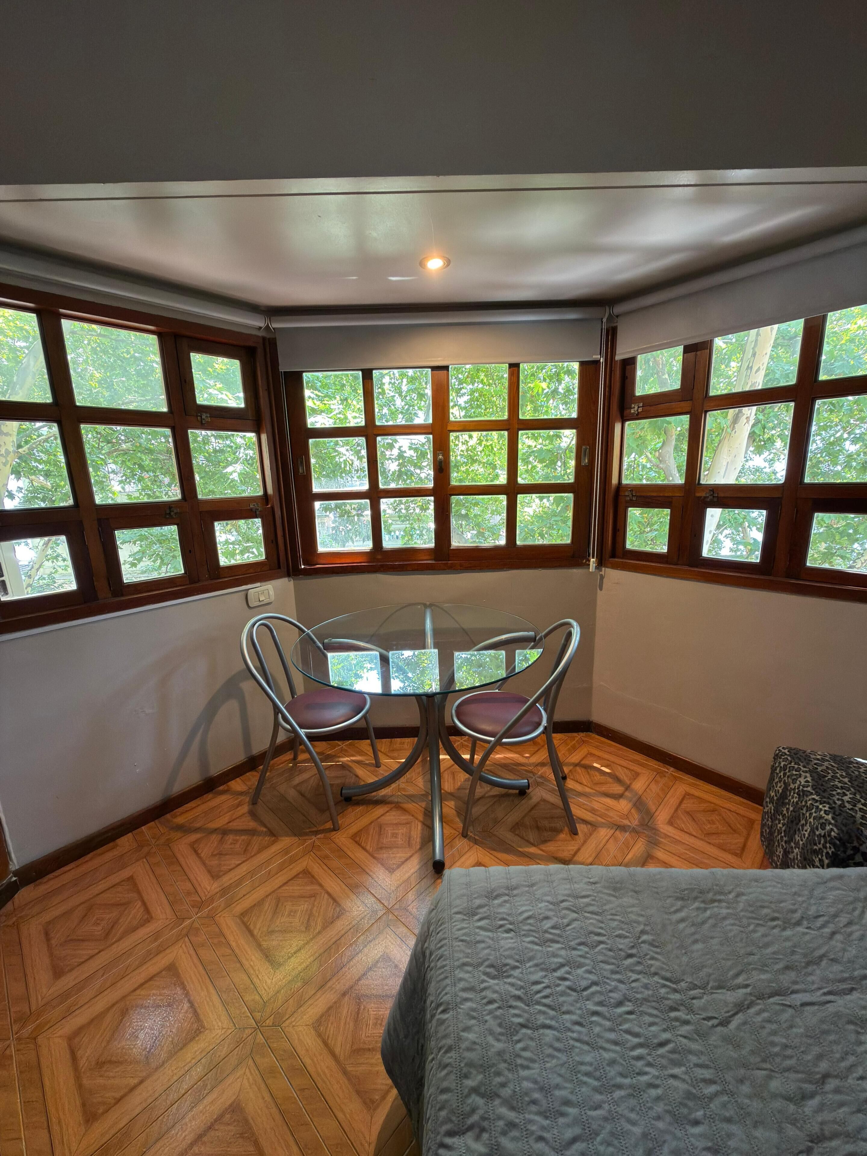 Una habitación con una mesa redonda de vidrio, dos sillas y una cama.