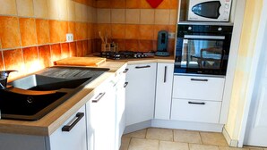 Een keuken met witte kastjes, een magnetron, een oven en een fornuis.