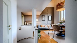Una escalera conduce a un espacio habitable con sofá, mesa de comedor, sillas y una lámpara colgante.