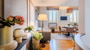 Una sala moderna con un sofá, una mesa de comedor y un televisor. Hay plantas en macetas y una lámpara.