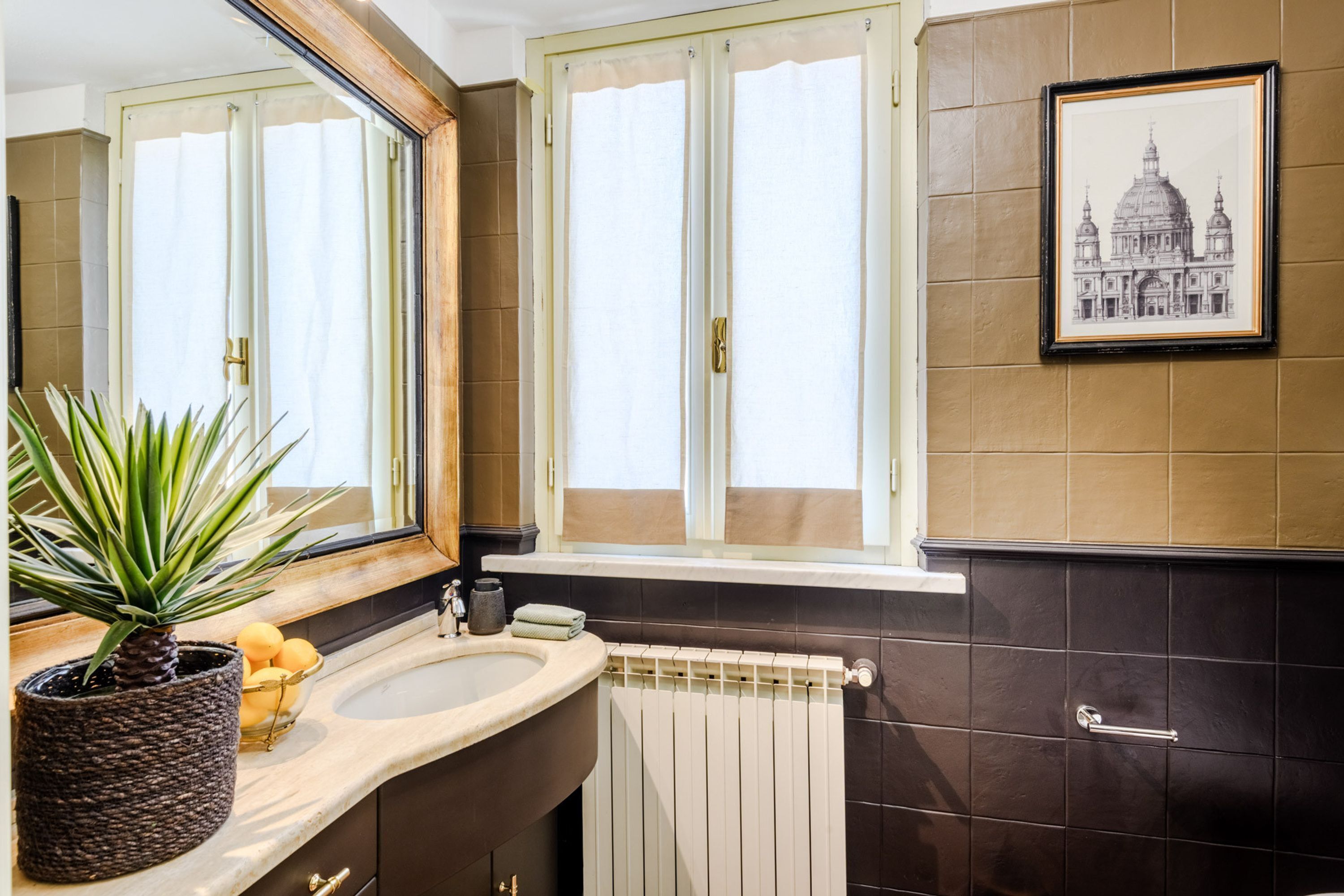 A bathroom with a large mirror, a sink, a towel rack, and a framed picture on the wall.