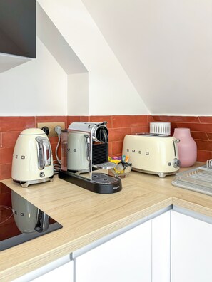 Eine Küche mit Kaffeemaschine, Toaster und Wasserkocher auf der Arbeitsfläche.
