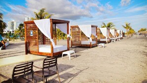 A beachside hotel with wooden cabanas, each with a bed and a small table and chair. - Playa Blanca Signature (Rio Hato)
