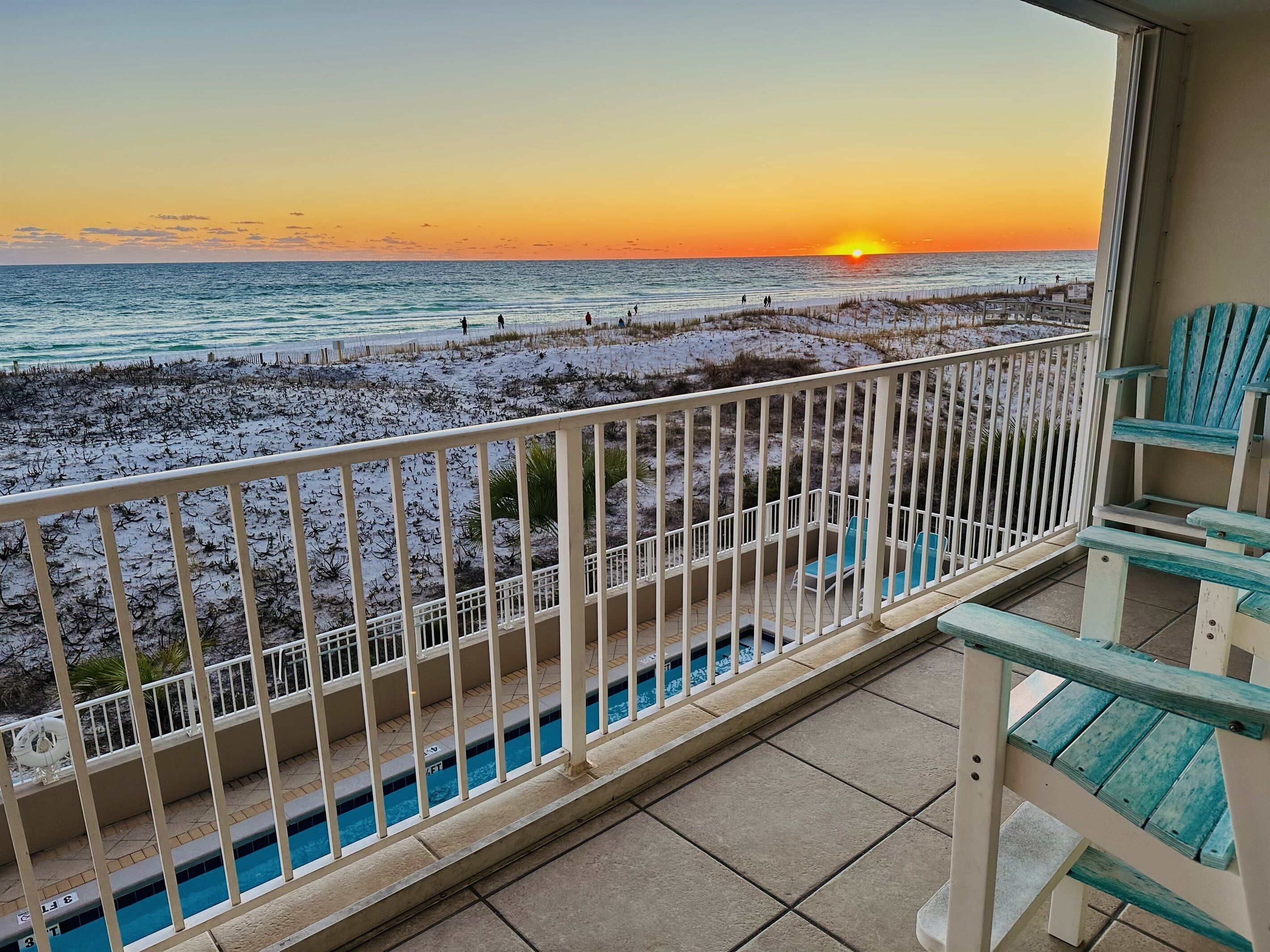 Un balcon avec vue sur la plage et l’océan au coucher du soleil.
