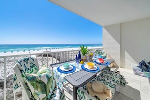 Un balcón con una mesa dispuesta para dos personas, con vista a una playa.