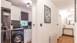 A compact kitchen with a washing machine, a sink, and a radiator. - Central & Seaside: Comfort (Great Yarmouth)