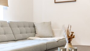 A modern living room with a grey sofa, a small table with a vase and a plate of pastries, and a framed picture on the wall. - Central & Seaside: Comfort (Great Yarmouth)