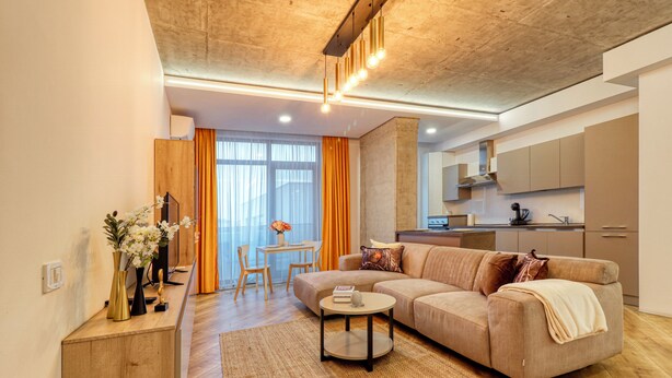 A modern living room with a sofa, coffee table, and a dining area with a table and chairs. - Soothing 1-bedroom apartment in Floreasca, București (București)