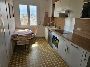 A compact kitchen with a dining area, a dishwasher, and a view through the window. - Spacious 2-Bedroom Apartment in Central Antibes (Antibes)