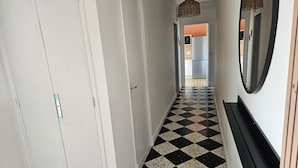 Ein Korridor mit Schachbrettfußboden, weißen Wänden und einem Spiegel auf der rechten Seite.