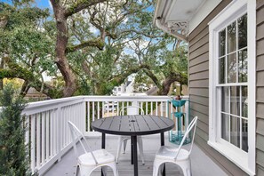 A covered outdoor area with a round table and chairs, a white railing, and large trees. - The Treehouse Walk to Forsyth, Balcony (Savannah)
