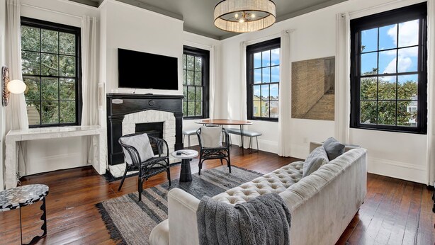 A living room with a fireplace, a television, a sofa, and large windows. - The Treehouse Walk to Forsyth, Balcony (Savannah)