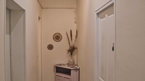 A narrow hallway with patterned flooring, a small cabinet, and a door. - Studio Apartment 'Centre Historique Beaucaire' with Wi-Fi (Beaucaire)
