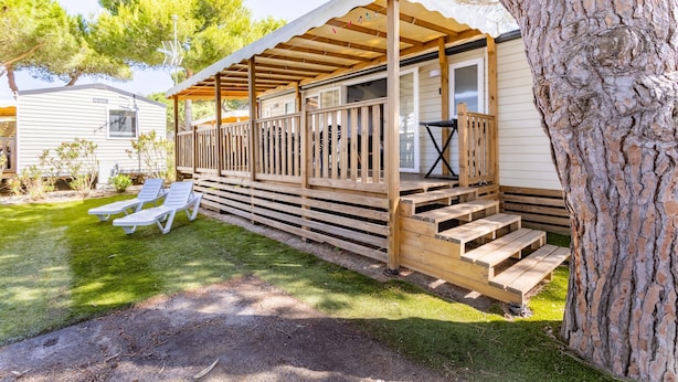 Una casa móvil con porche, una pequeña terraza y un patio con césped.