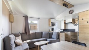 Un espacio habitable compacto con sofá, mesa de comedor, zona de cocina y un reloj en la pared.