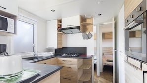 Cocina compacta con microondas, estufa y lavamanos.
