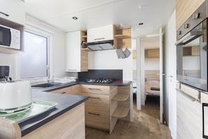 Une cuisine de taille réduite équipée d’un four à micro-ondes, d’une cuisinière et d’un évier.