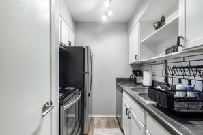 A compact kitchen with a stove, refrigerator, and sink. - Arlington 2BR | AT&T, Globe Life, 6 Flags, Parking (Arlington)