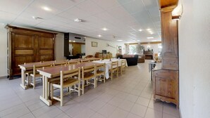 Ein Essbereich mit Holztischen und -stühlen, im Hintergrund eine Küche und ein großer Holzschrank.