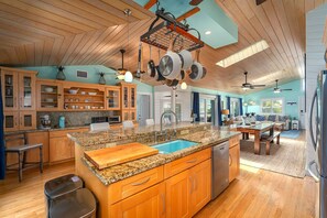 A spacious kitchen with granite countertops, wooden cabinets, and a central island with a sink. - Green Turtle Oasis: 4BR Canal Front Home, Pool, Dockage, Outdoor Dining & Pets (Sugarloaf Key)