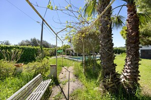 A garden with a bench, palm trees, and a swimming pool. - Casa das Camélias: Private Pool, Terrace & Wi-Fi (Luz)