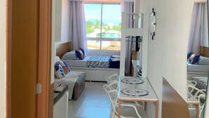 A compact hotel room with a bed, a small table, and a chair. - Your complete studio apartment in Porto de Galinhas, sun and sea! (Ipojuca)