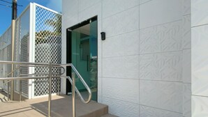 A modern building exterior with a metal staircase, a glass door entrance, and a patterned wall. - Your complete studio apartment in Porto de Galinhas, sun and sea! (Ipojuca)